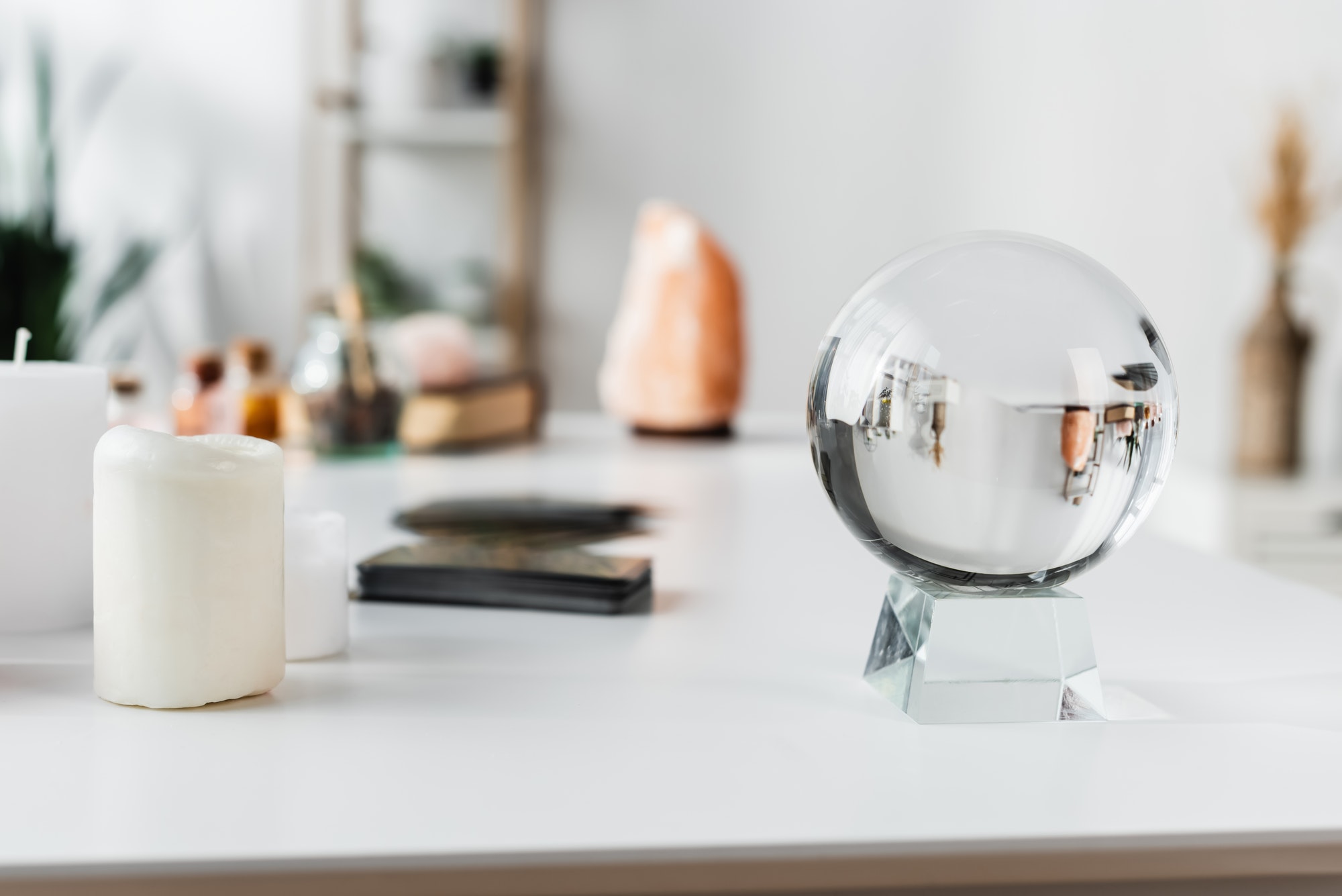 Glass orb near candles and blurred tarot cards on table